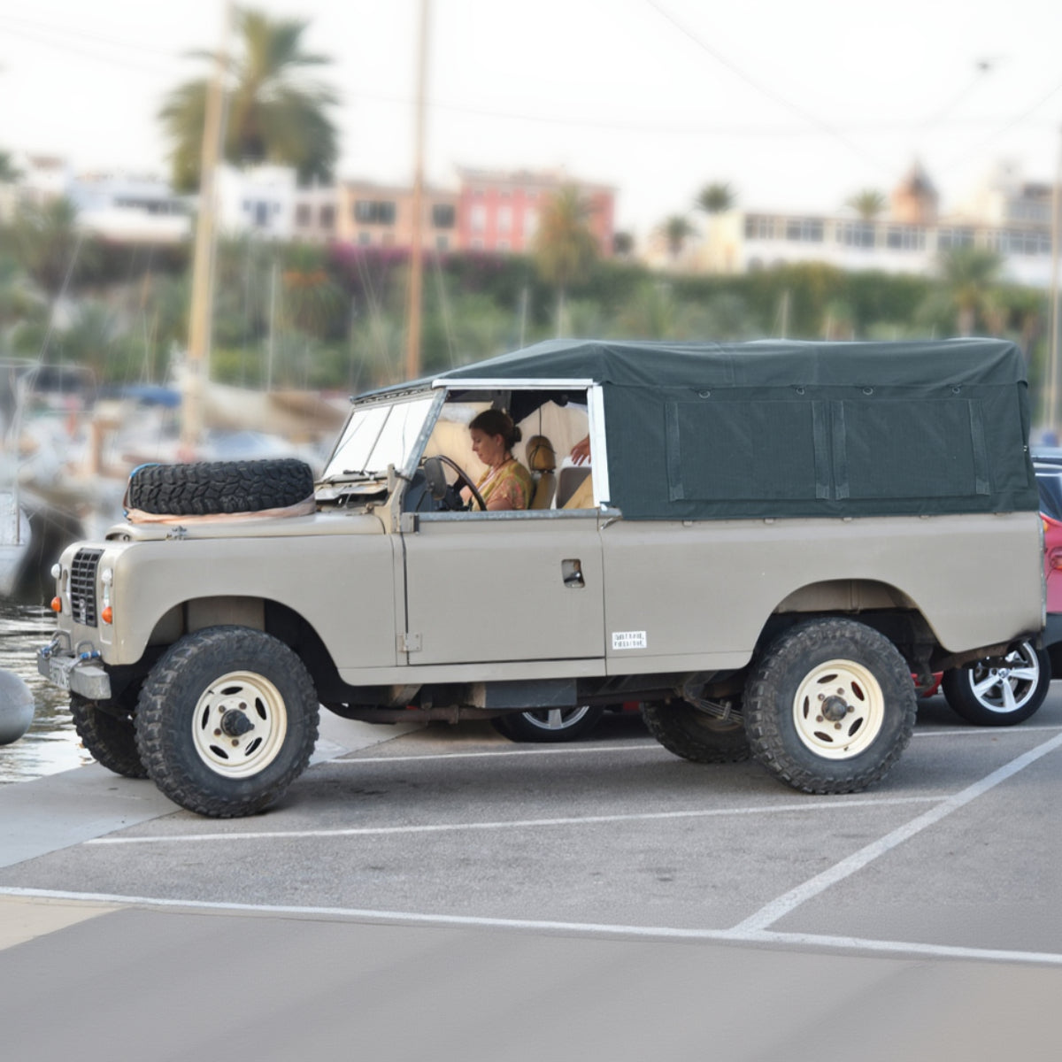 Vintage Land Rover Series III with a black soft top in a parking lot.