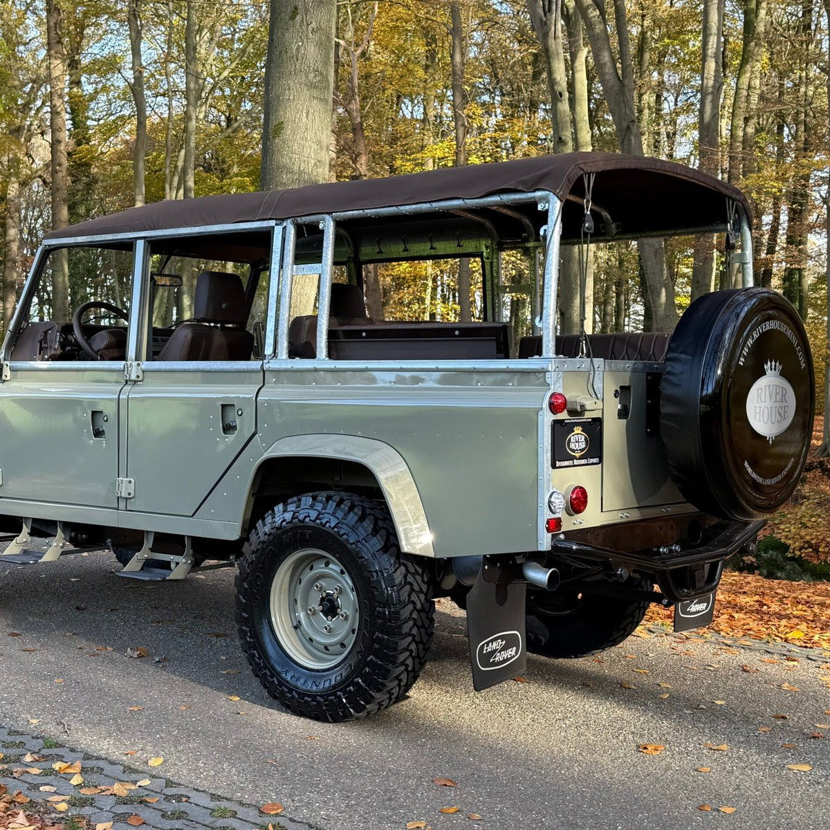 Vintage Land Rover Defender parked on a road with trees in the background