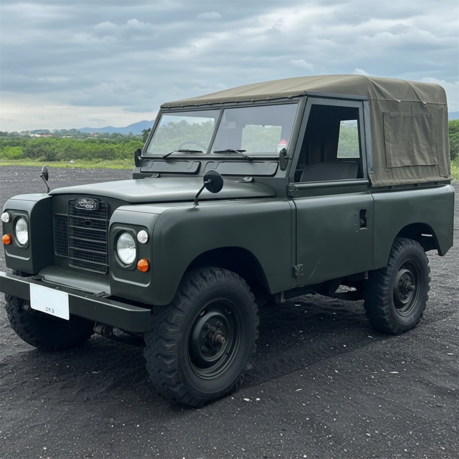 Green vintage jeep on a road with a scenic background