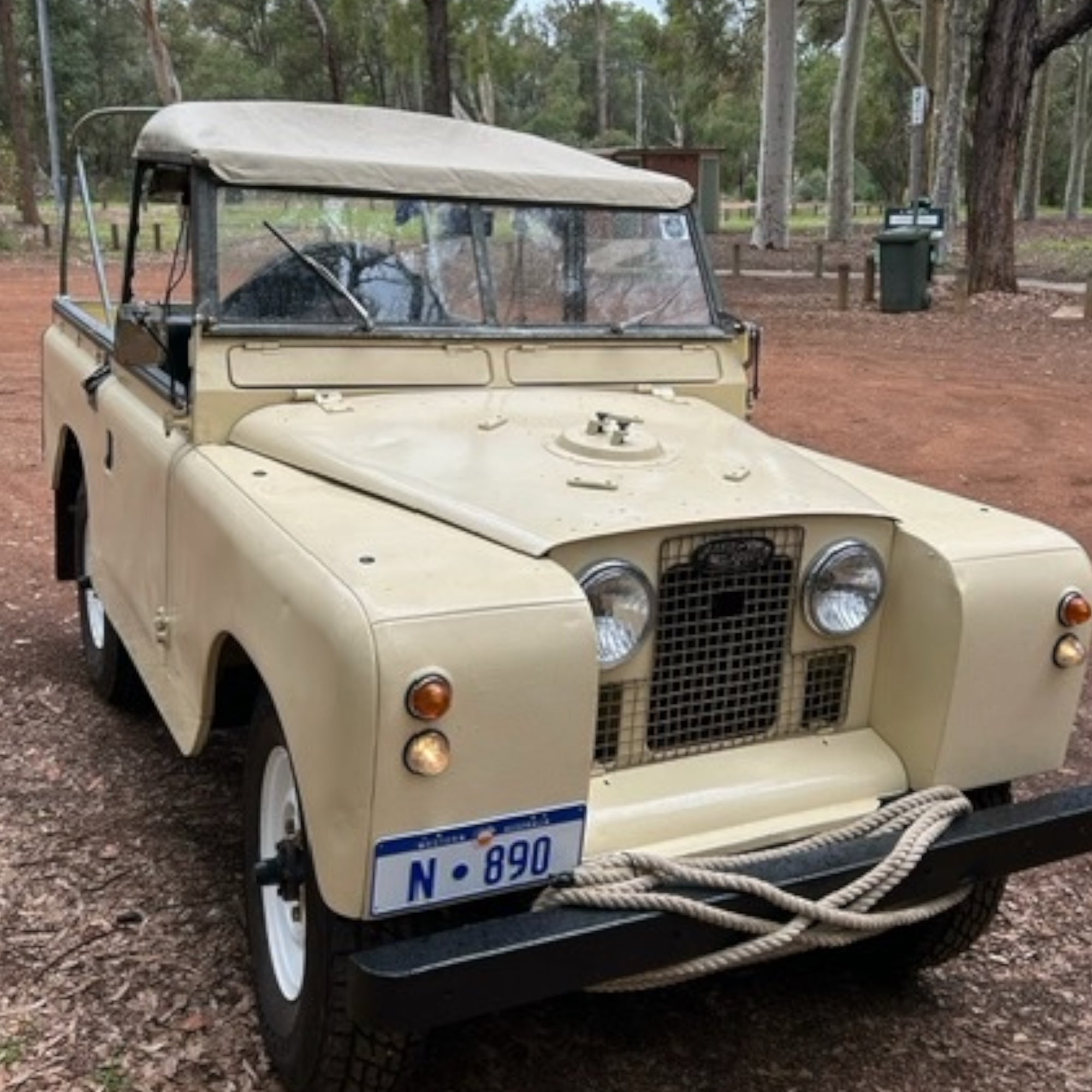 Beige vintage Land Rover with a canopy in an outdoor setting