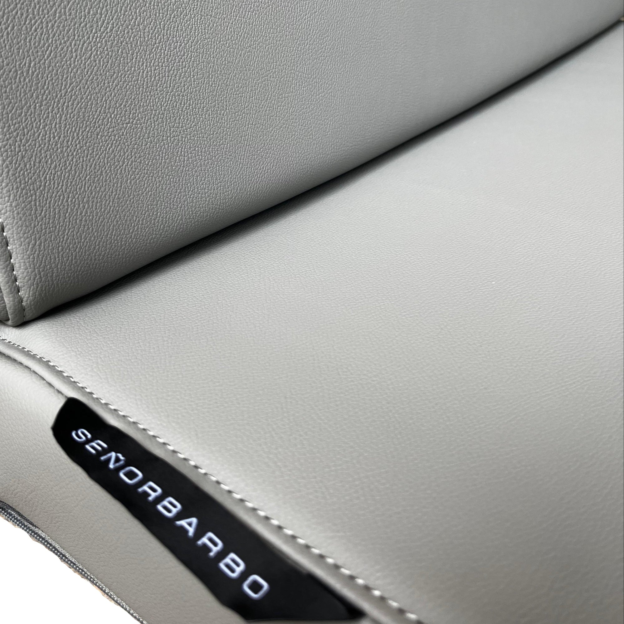 Close-up of a gray leather seat with &#39;Senoobarbo&#39; branding.