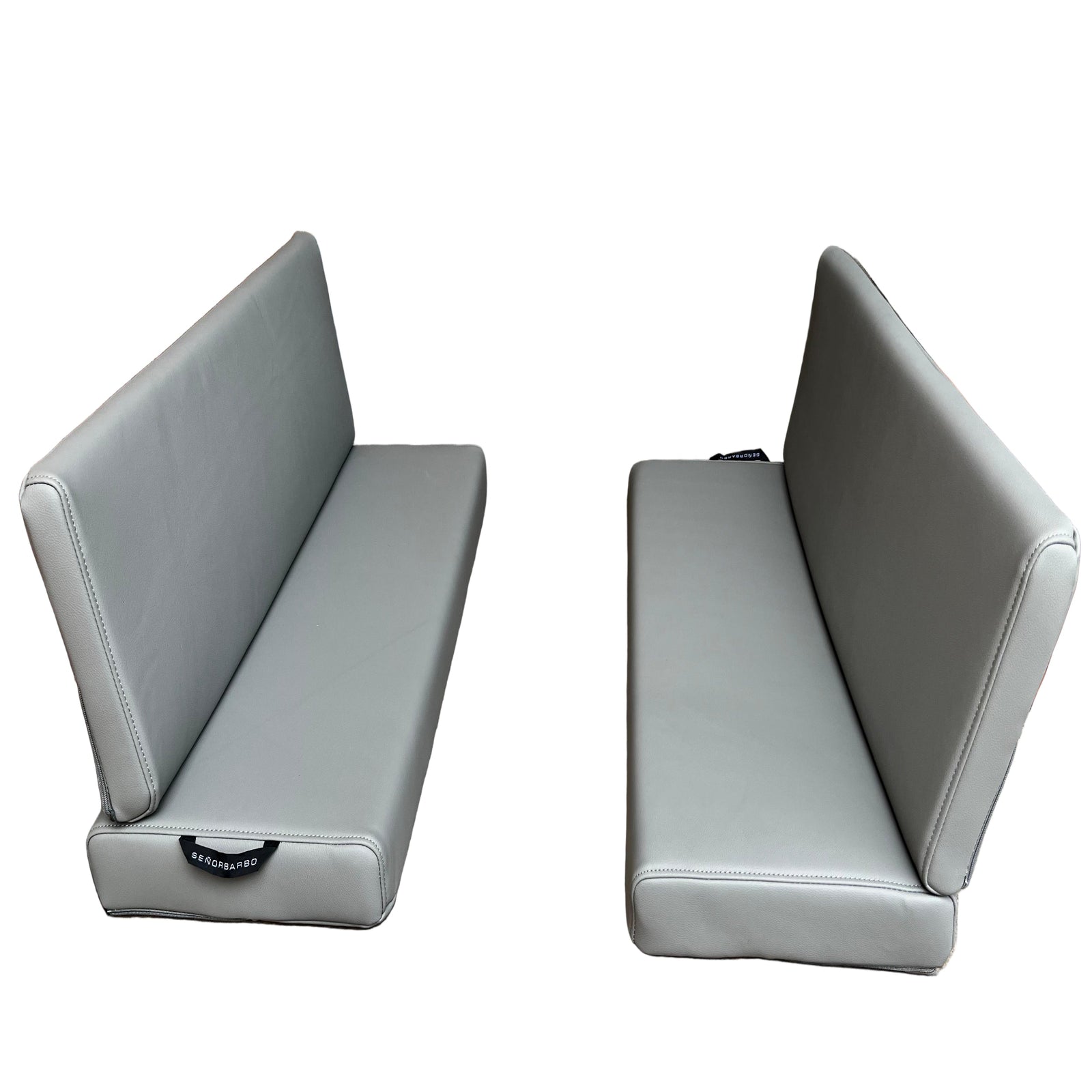 Two gray cushioned benches against a wooden wall and concrete floor.