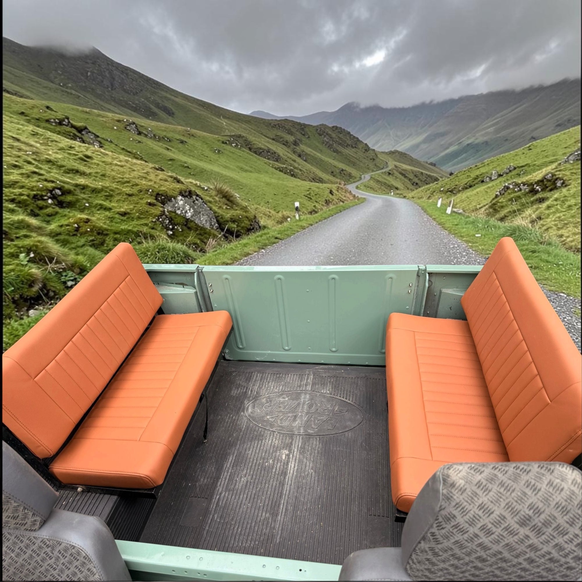 Open-top vehicle with orange seats overlooking a scenic mountain road.