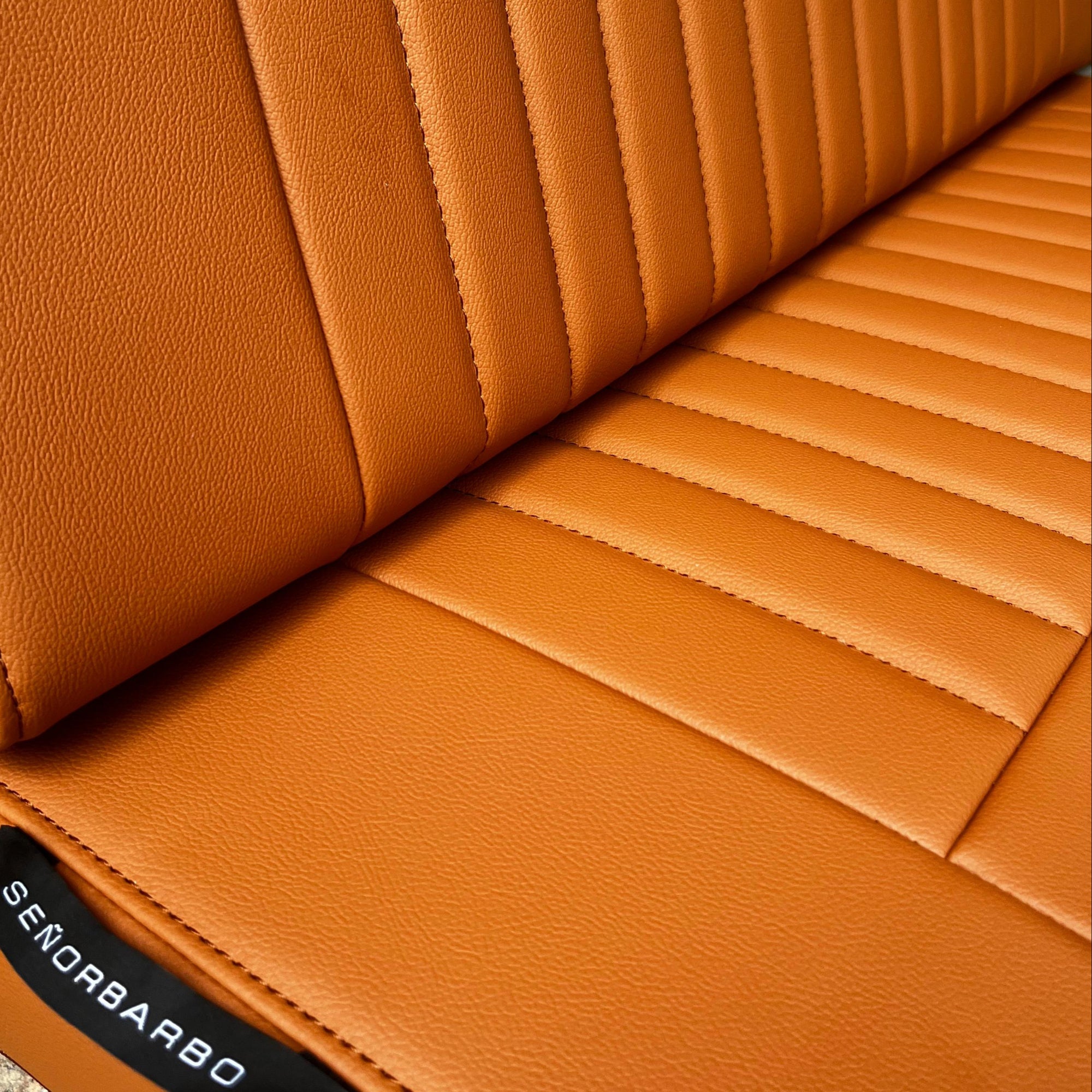 Close-up of a brown leather seat with a brand label on a textured surface.