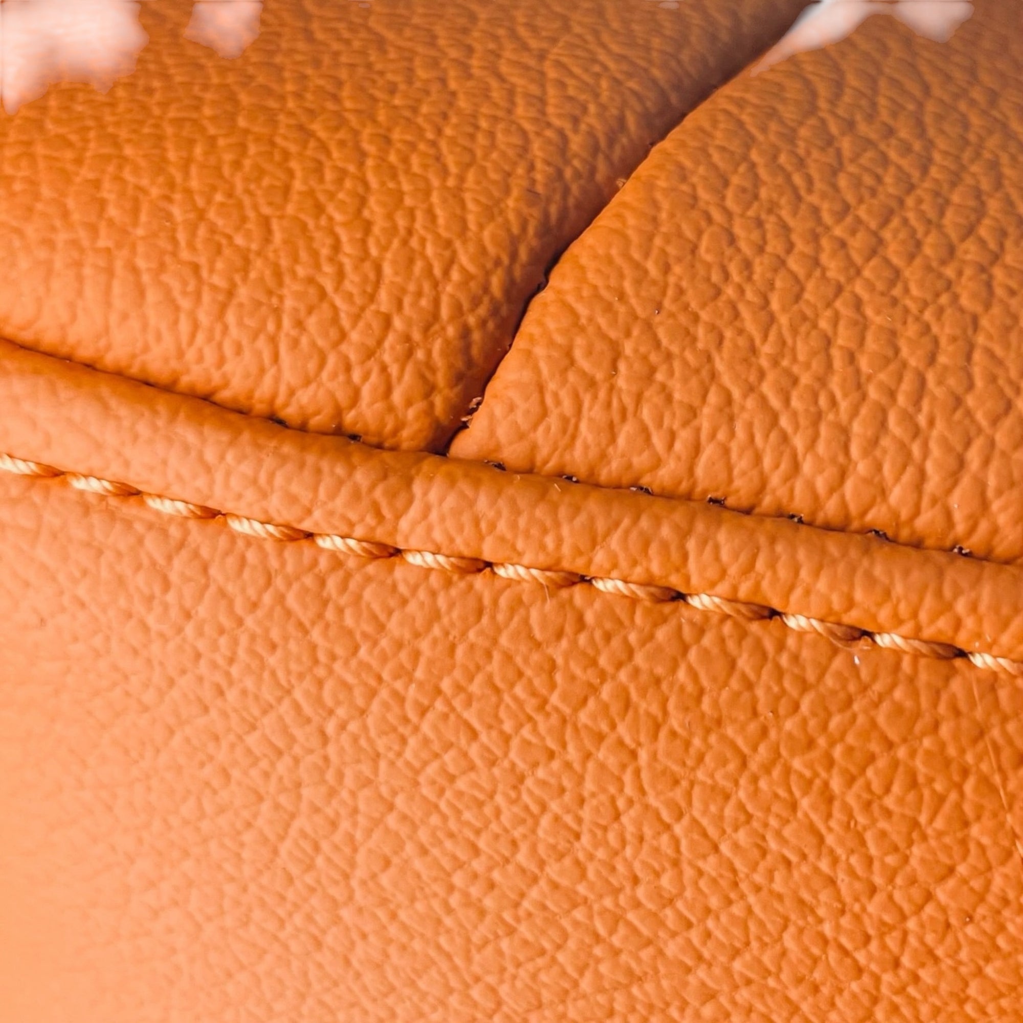Close-up of orange leather with visible stitching