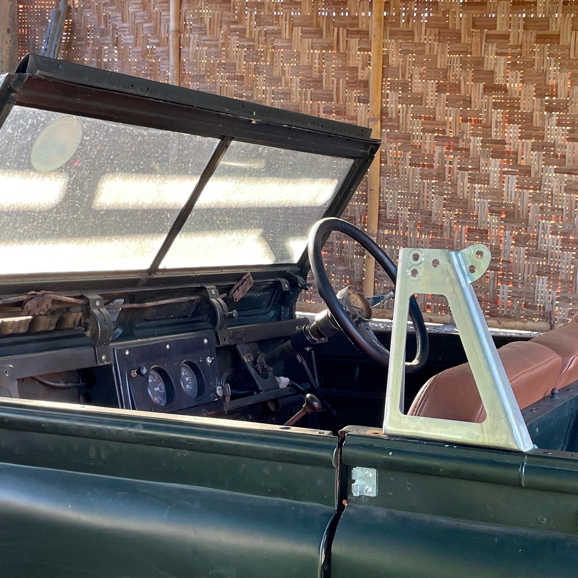 Interior of a vintage vehicle with a steering wheel and dashboard, against a textured wall.