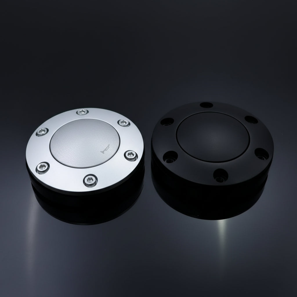 Two metallic objects, one silver and one black, on a dark reflective surface.