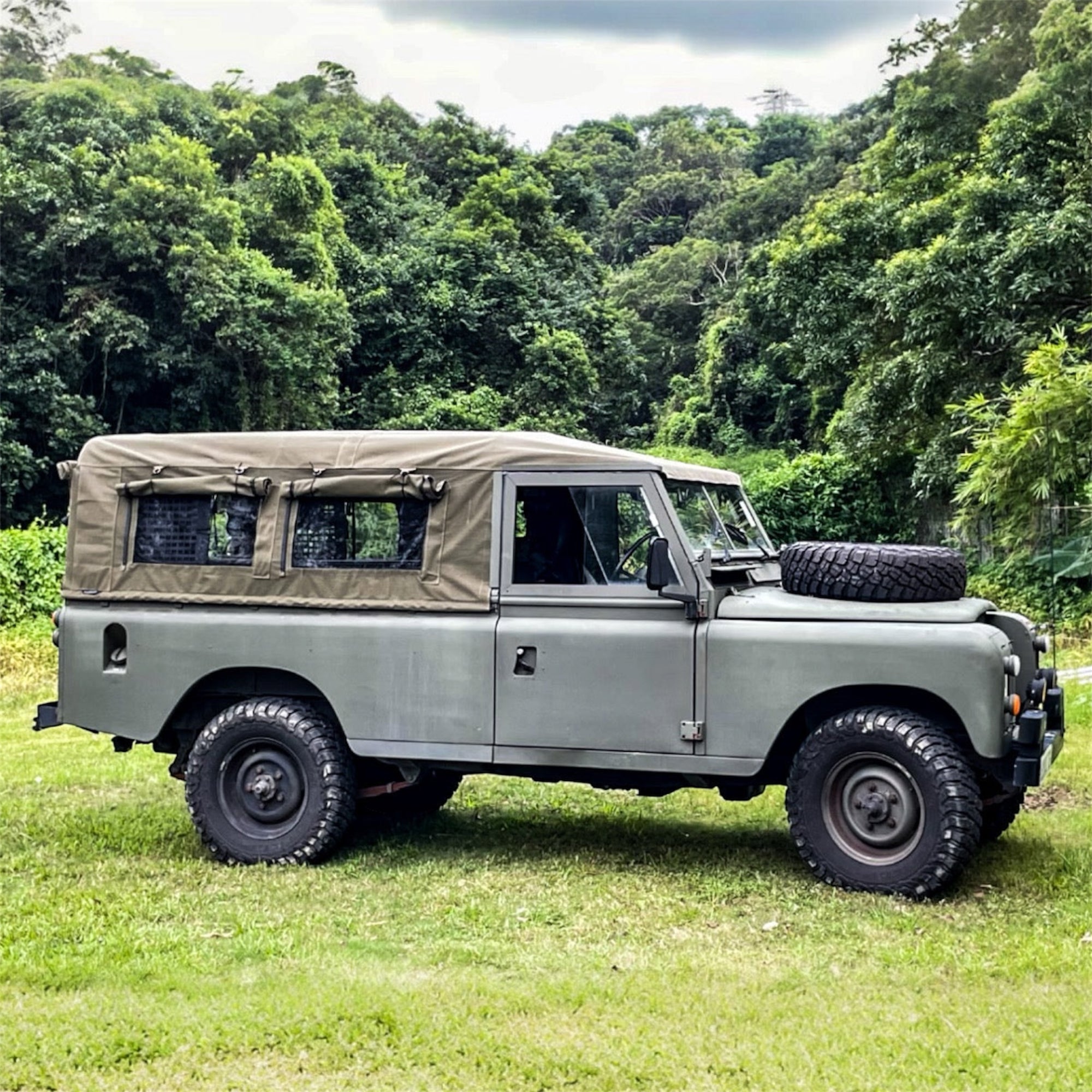 Green off-road vehicle with a roof rack in a forest setting