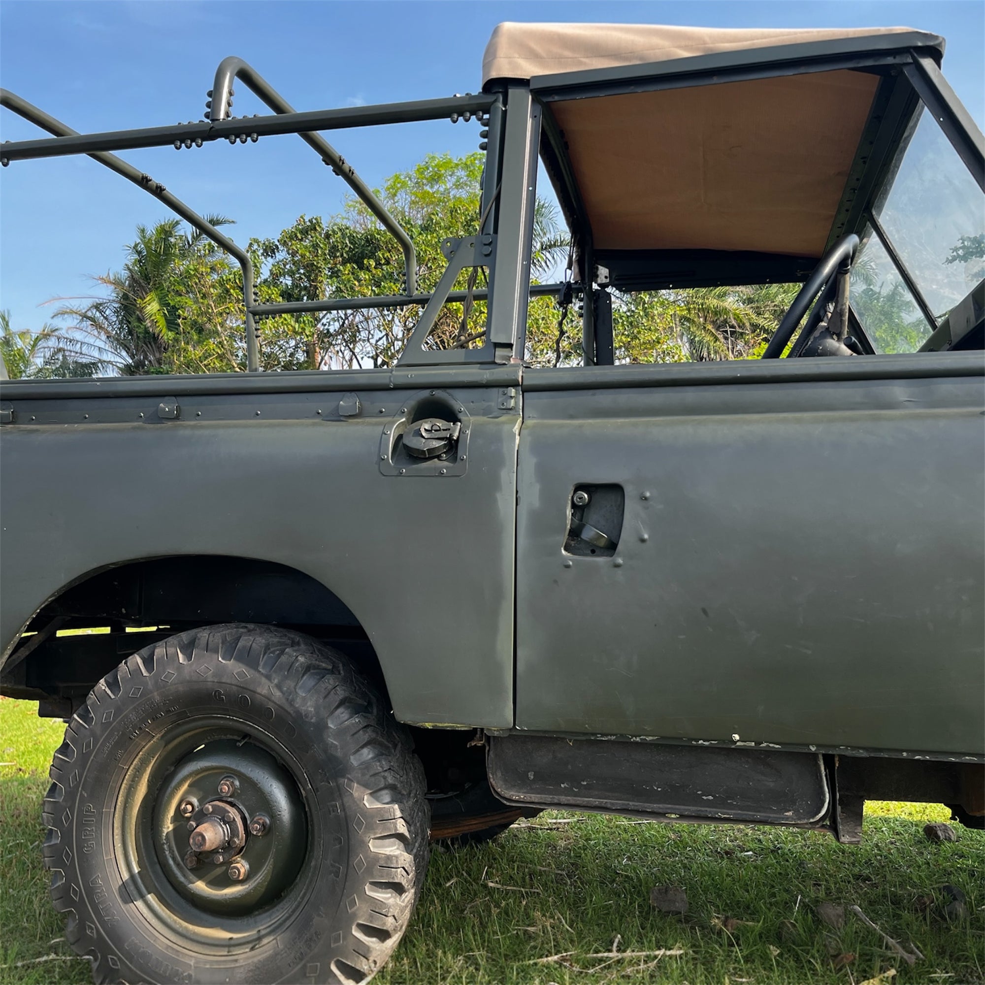 Green off-road vehicle with a roll bar on grassy terrain