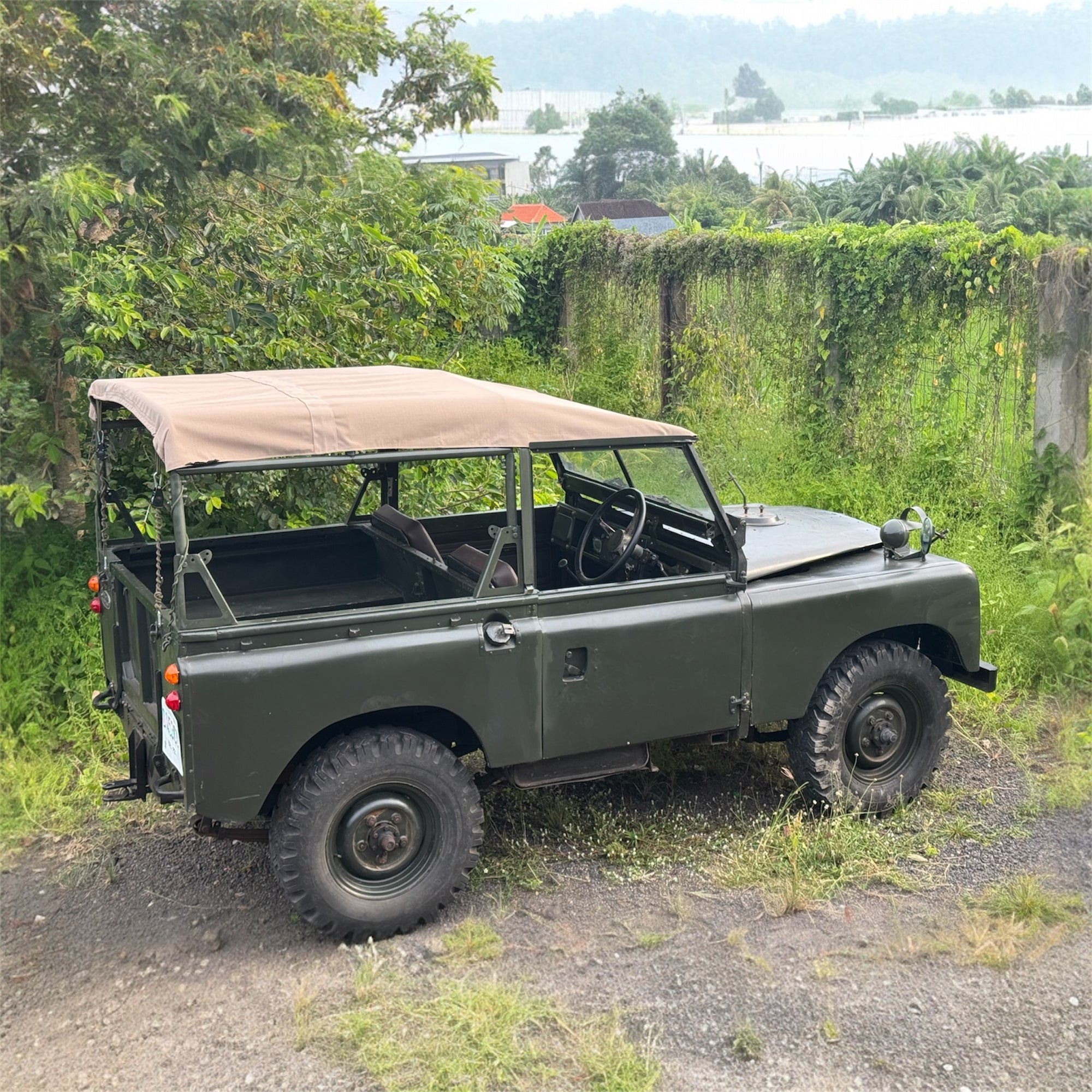 Green off-road vehicle with a tan roof in a natural setting