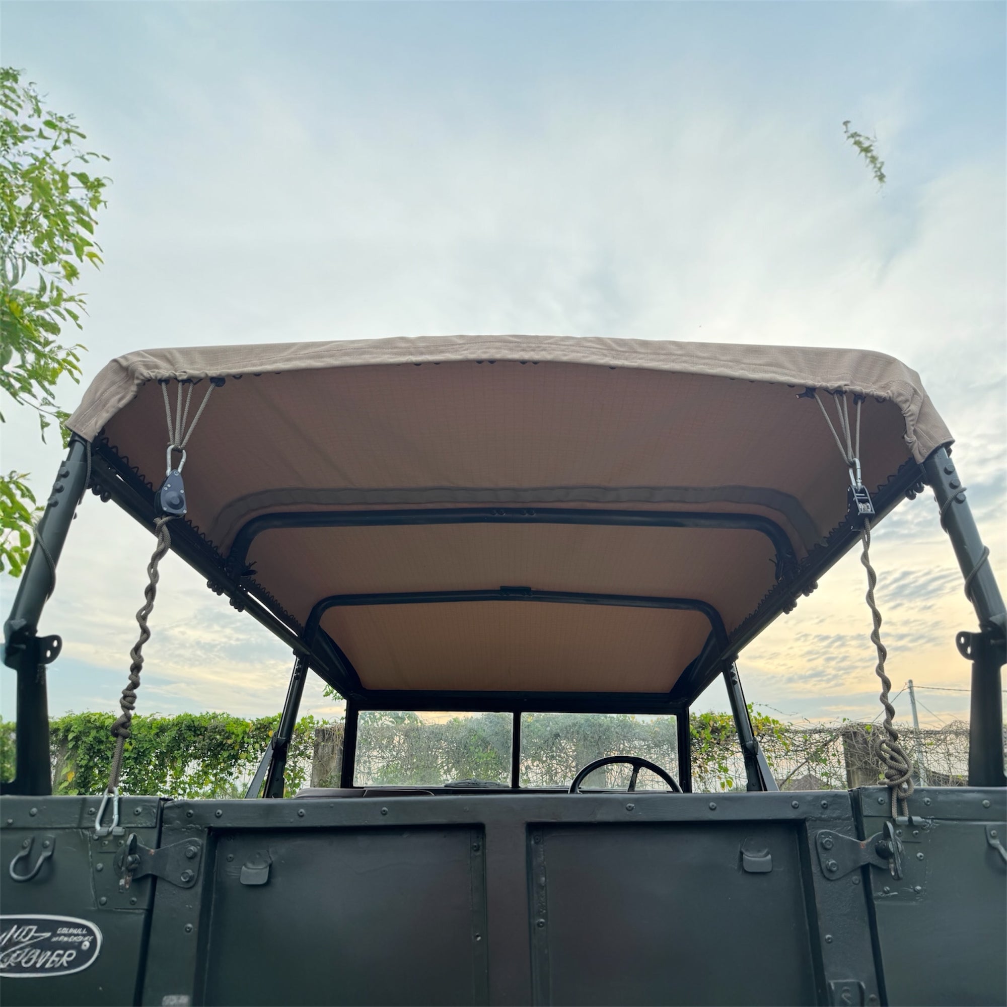 Open-top vehicle with a beige roof cover against a scenic background