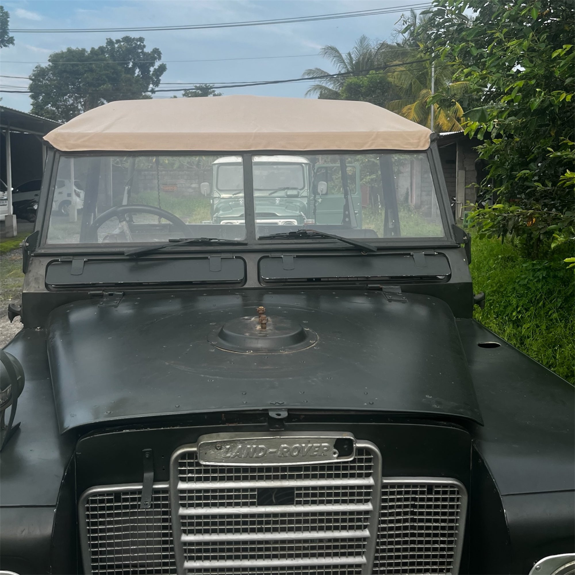 Vintage Land Rover with a beige roof in an outdoor setting