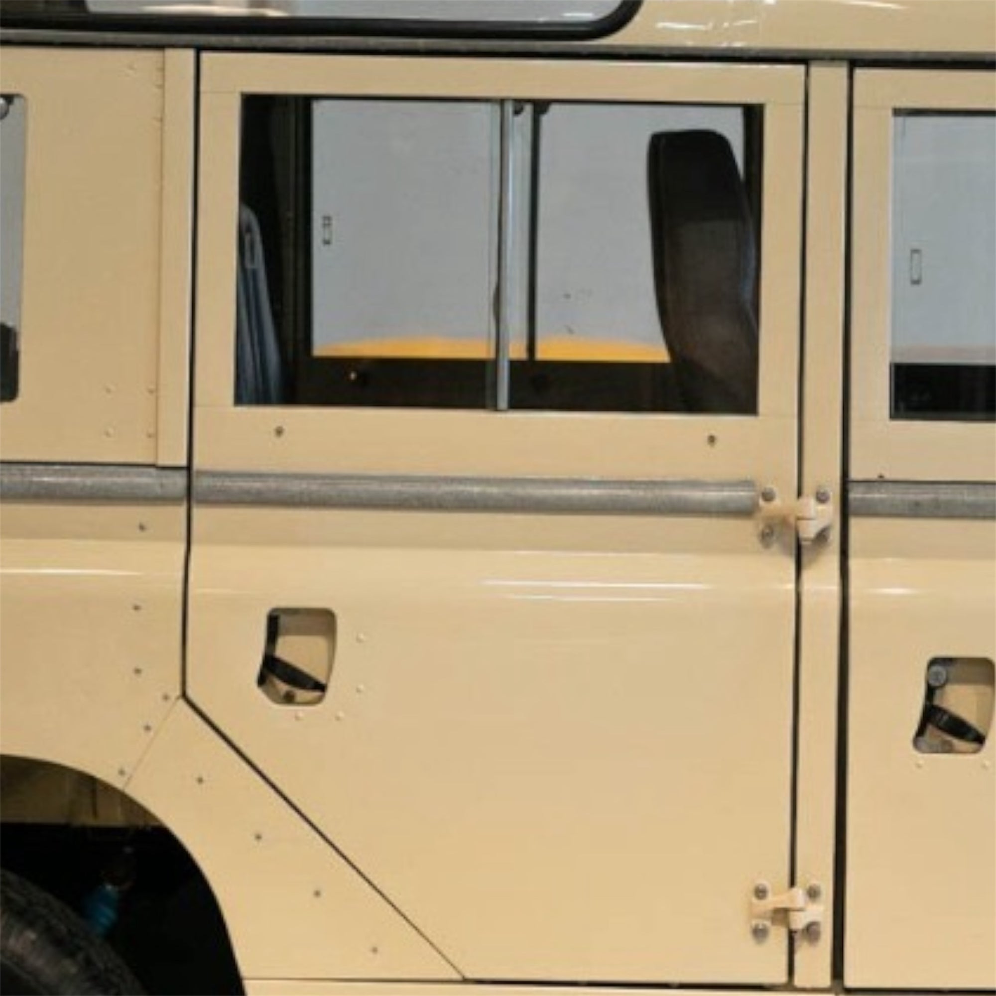 Close-up of a beige vehicle door with a window, showing wear and tear.