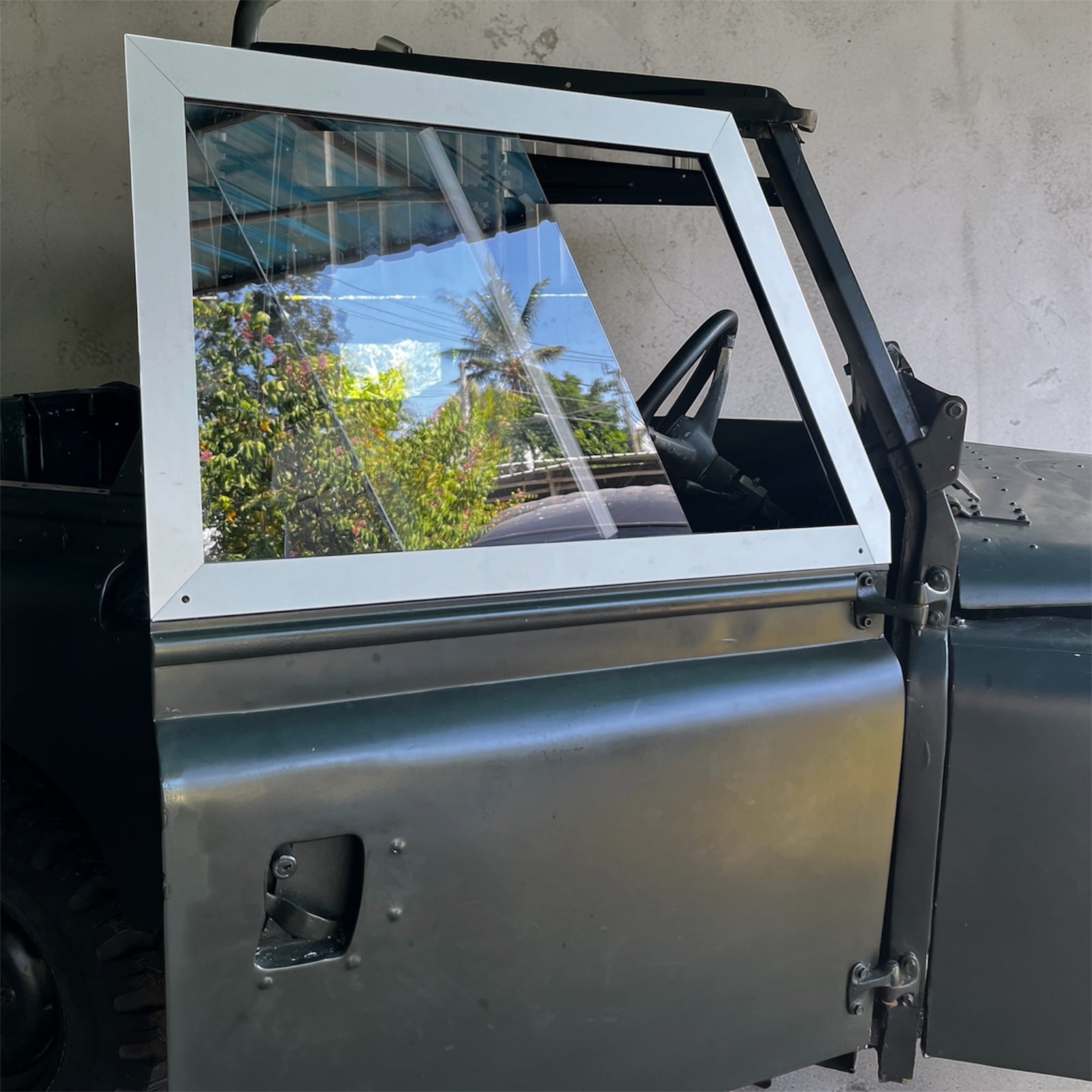 Metallic vehicle door with a window and visible interior, outdoors.