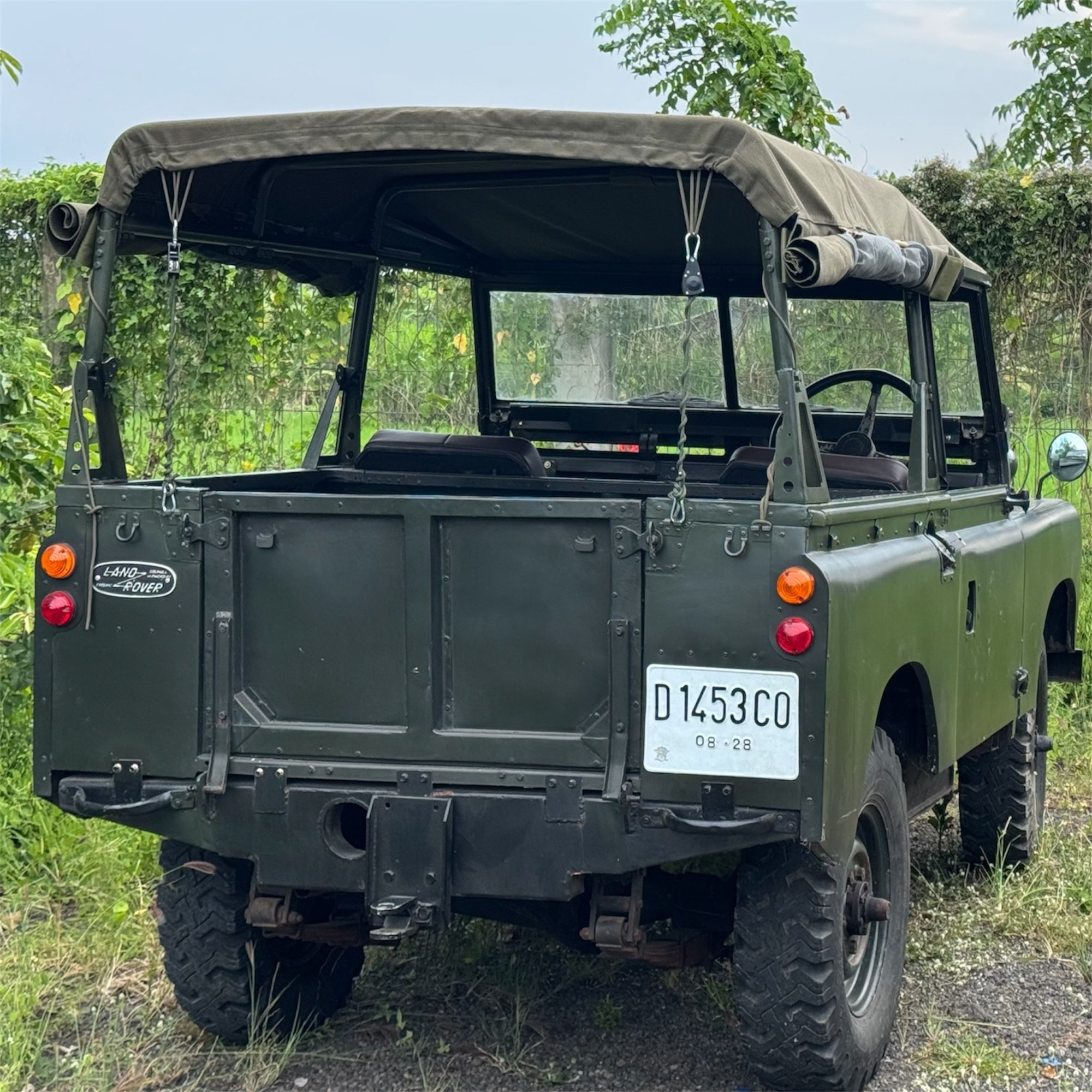 Green Land Rover vehicle with a canopy in a natural setting