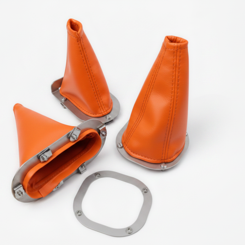 Orange leather gear shift boot with metal components on a white background