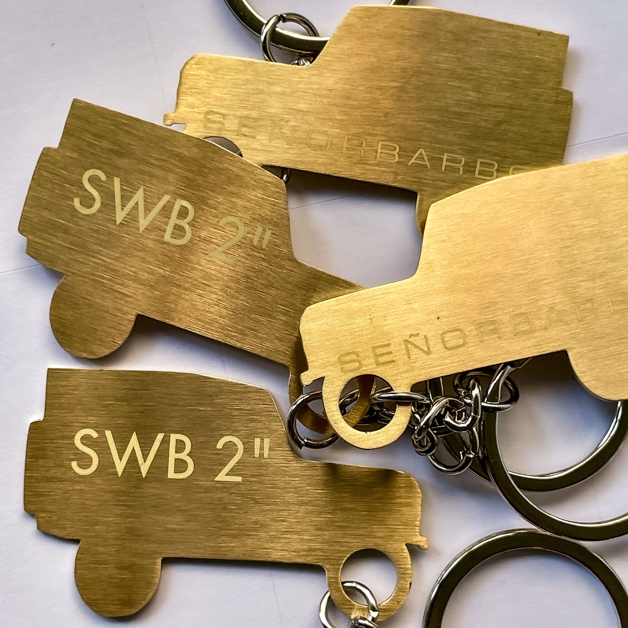 Gold truck-shaped keychains with engraved text on a white background